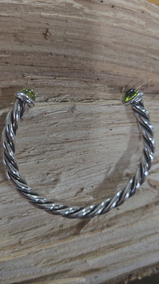 Twisted sterling silver oxidized cuff bracelet with cabachon peridot ends.