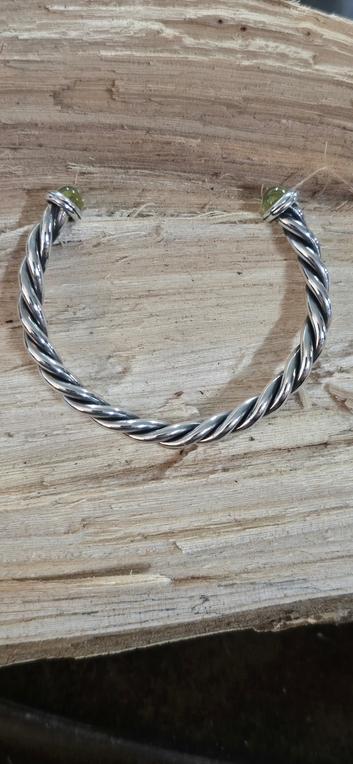 Twisted sterling silver oxidized cuff bracelet with cabachon peridot ends.